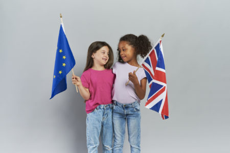 Niñas abrazando y sosteniendo banderas británicas y de la Unión Europea, uniendose en los estudios